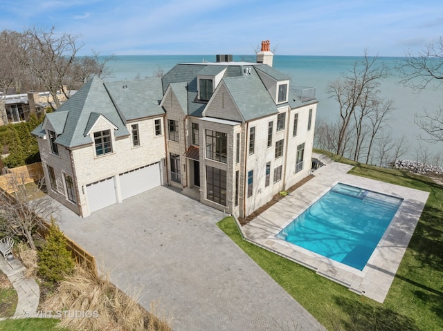 rear view of property featuring a water view, a garage, and a patio area