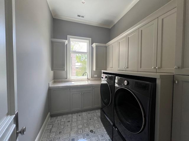 clothes washing area with light tile patterned flooring, cabinets, sink, and washing machine and clothes dryer