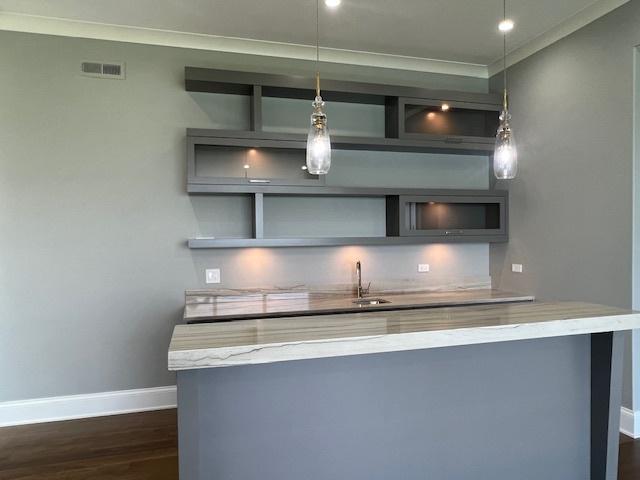 kitchen featuring light stone countertops, dark hardwood / wood-style floors, ornamental molding, and decorative light fixtures