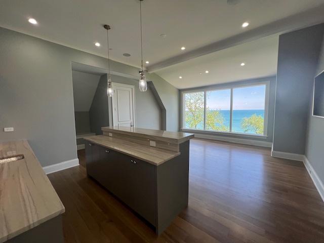 kitchen featuring dark hardwood / wood-style floors, hanging light fixtures, a water view, and a center island