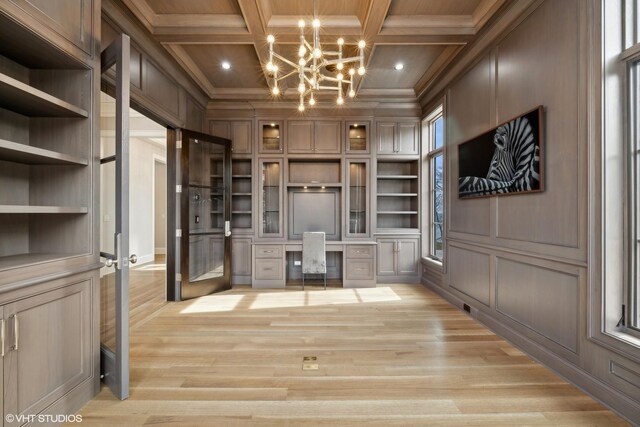 unfurnished office featuring beam ceiling, french doors, coffered ceiling, an inviting chandelier, and light wood-type flooring