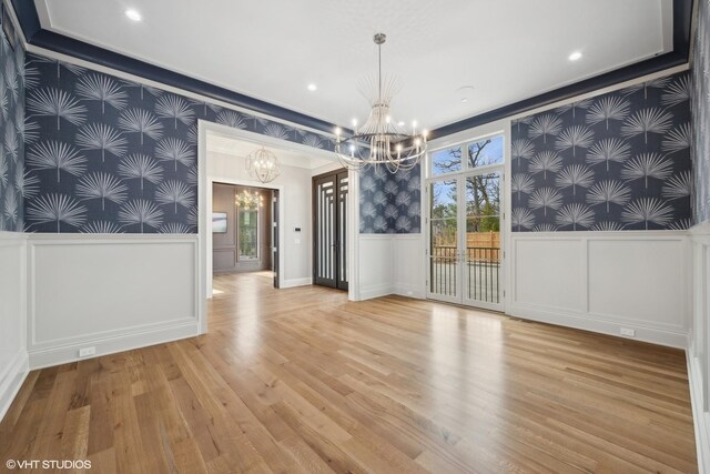 unfurnished room featuring light wood-type flooring and an inviting chandelier