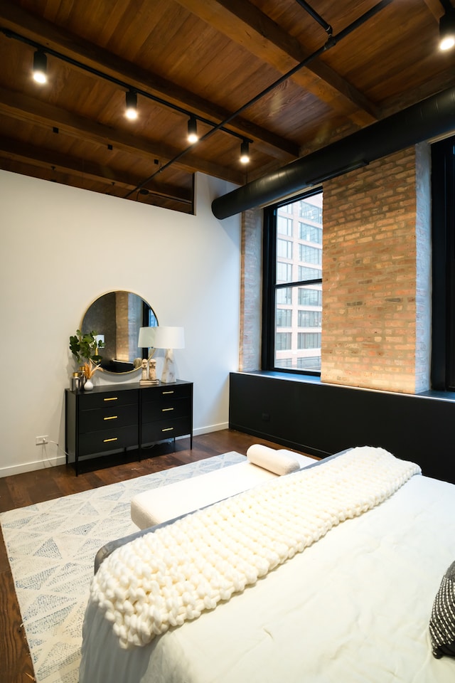 bedroom featuring dark wood-type flooring, beam ceiling, and wood ceiling