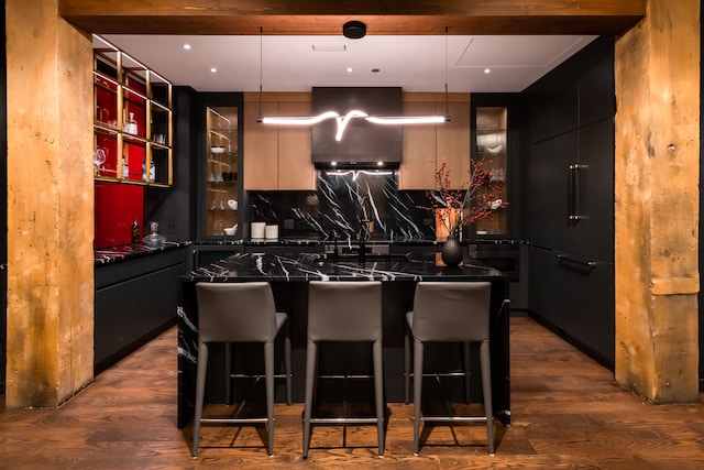 kitchen with hardwood / wood-style floors, decorative backsplash, pendant lighting, and a breakfast bar area