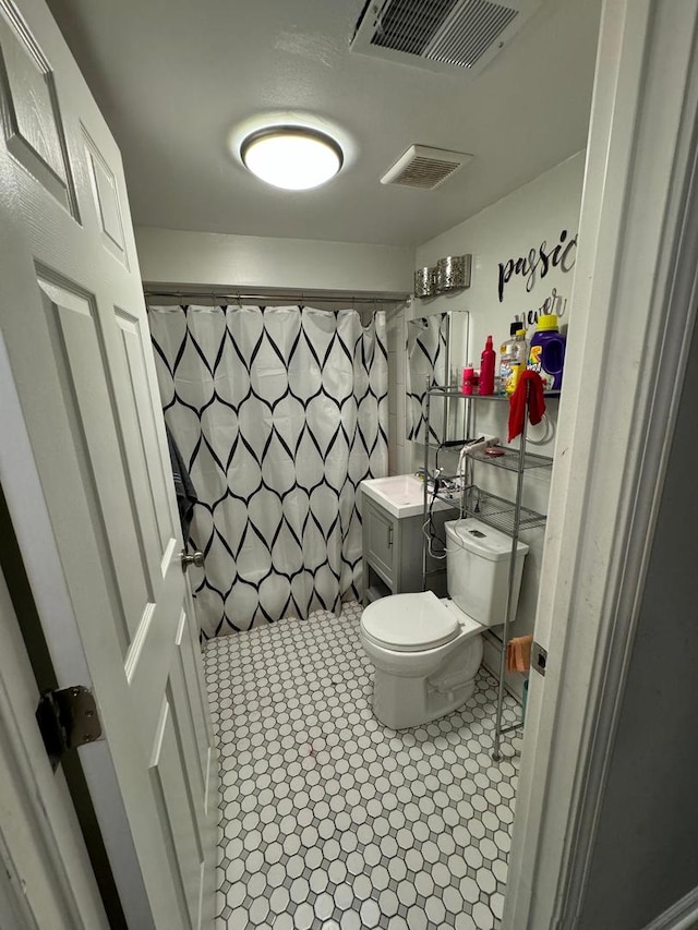 bathroom featuring toilet, tile patterned flooring, vanity, and curtained shower