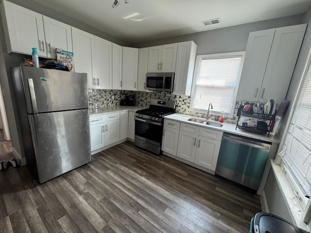 kitchen with sink, backsplash, dark wood-type flooring, white cabinetry, and stainless steel appliances