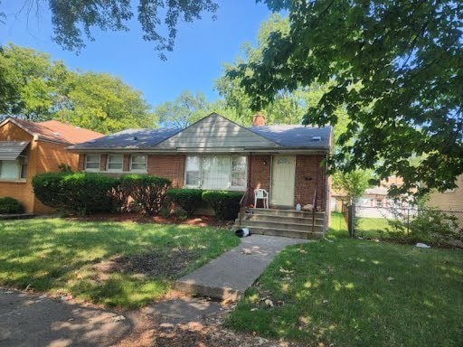 ranch-style house featuring brick siding, fence, and a front yard