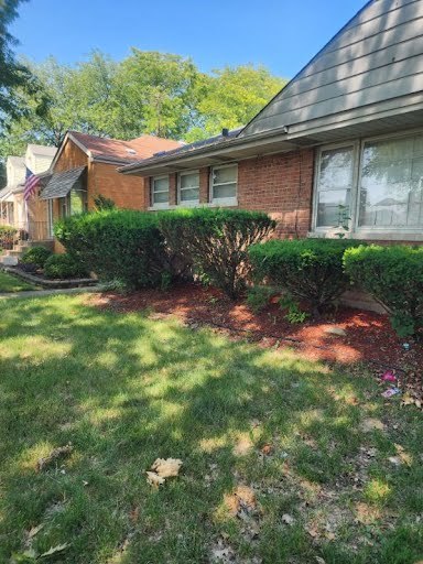 view of side of property with brick siding and a yard