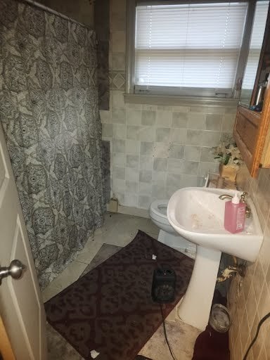 bathroom with tile walls, tile patterned floors, and toilet