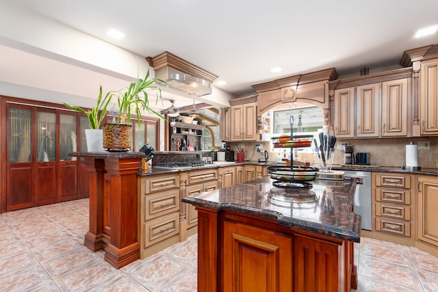 kitchen featuring appliances with stainless steel finishes, backsplash, dark stone countertops, and a kitchen island