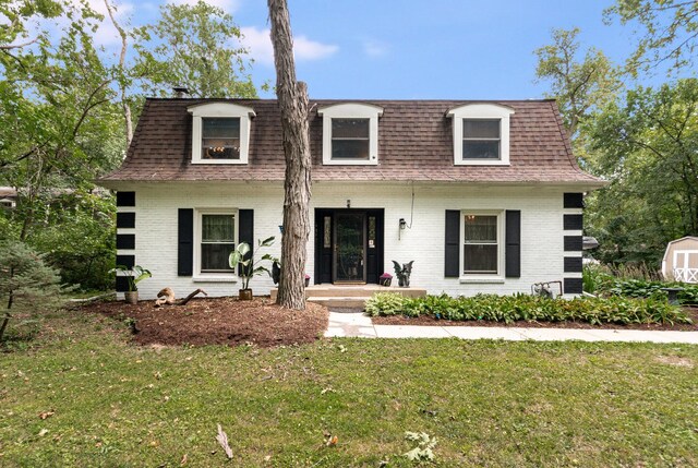 view of front of house with a storage shed and a front yard