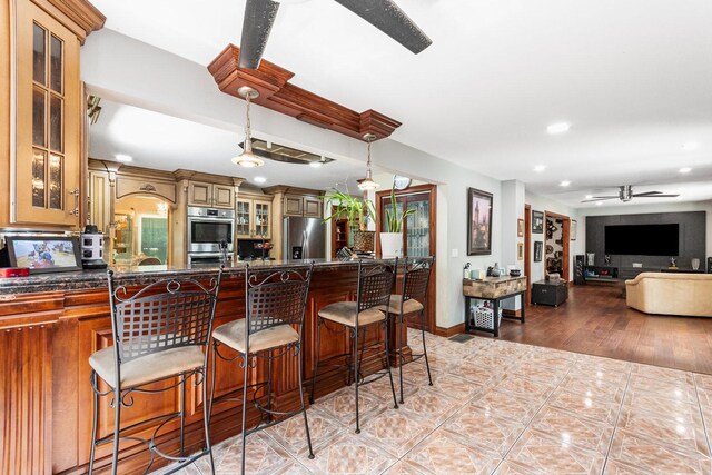 kitchen featuring ceiling fan, appliances with stainless steel finishes, a kitchen breakfast bar, and pendant lighting