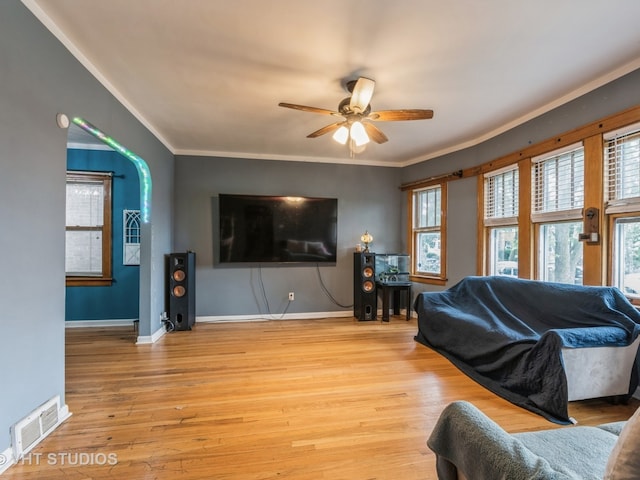 living room with light wood-type flooring, ornamental molding, and ceiling fan