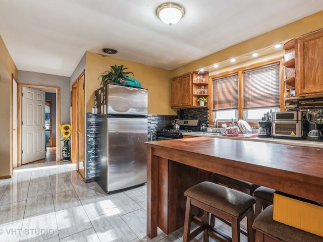 kitchen with decorative backsplash, stainless steel fridge, and gas range oven