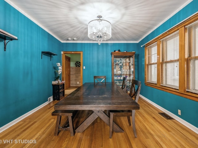 dining space featuring crown molding, a chandelier, and light wood-type flooring