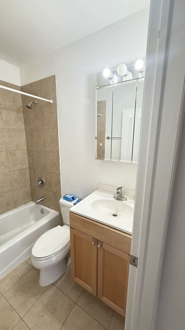 full bathroom featuring vanity, tile patterned flooring, toilet, and tiled shower / bath