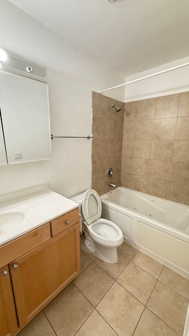 full bathroom featuring tile patterned flooring, tiled shower / bath, vanity, and toilet