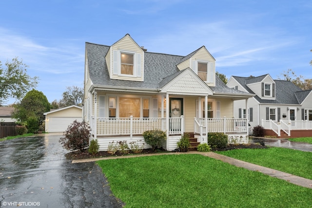 new england style home featuring a porch, a garage, and a front yard