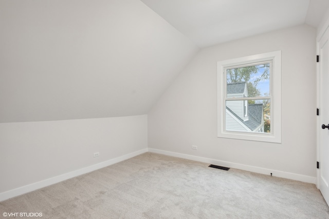 additional living space with light colored carpet and vaulted ceiling