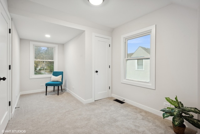 living area with a wealth of natural light and light colored carpet