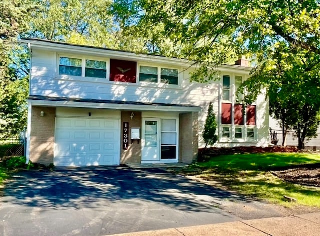 view of front of property featuring aphalt driveway, a garage, brick siding, and a chimney