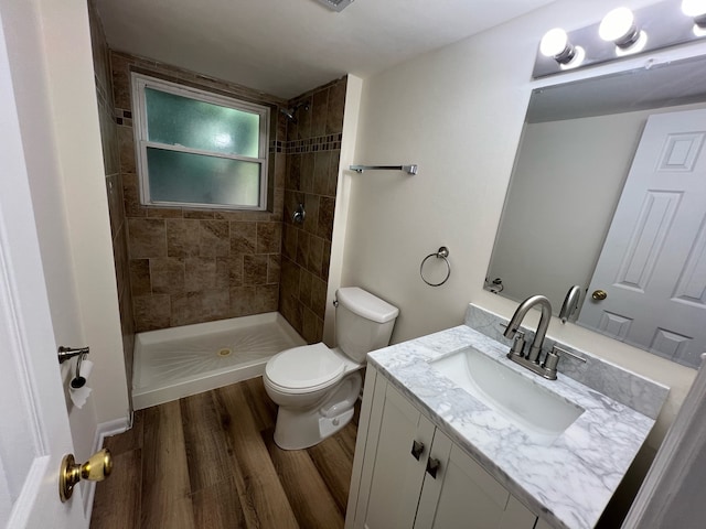 bathroom featuring vanity, toilet, wood-type flooring, and a tile shower