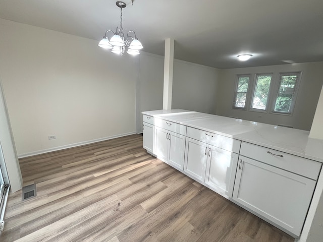 kitchen featuring light hardwood / wood-style floors, white cabinetry, hanging light fixtures, and an inviting chandelier