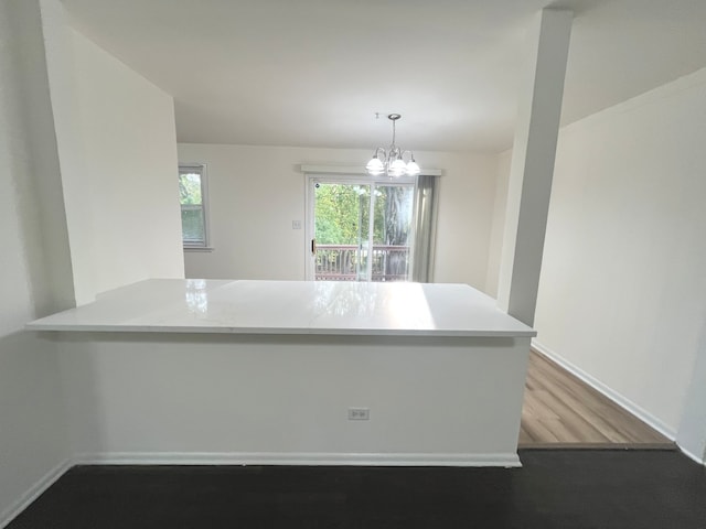 kitchen featuring pendant lighting, light hardwood / wood-style floors, kitchen peninsula, and an inviting chandelier