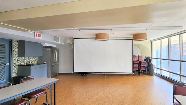 home theater with light wood-type flooring, a sink, and visible vents