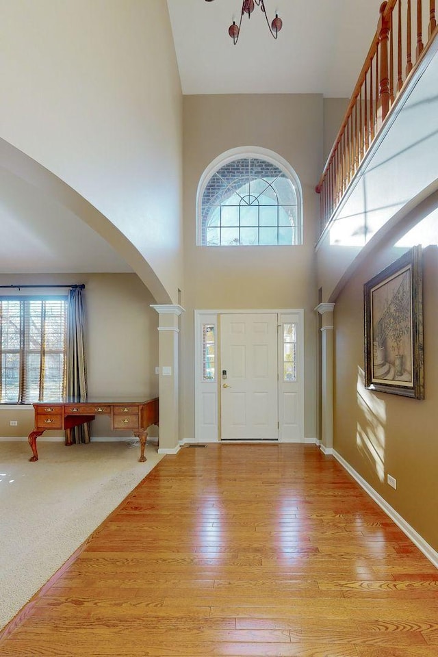 entrance foyer featuring a healthy amount of sunlight, light wood-type flooring, and a towering ceiling