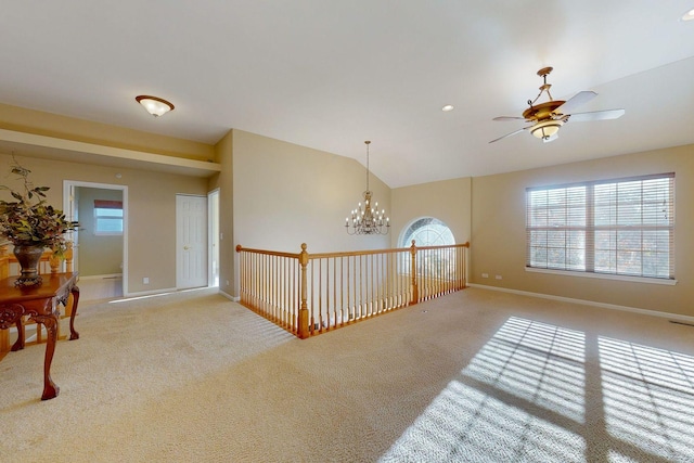 carpeted spare room with lofted ceiling and ceiling fan with notable chandelier