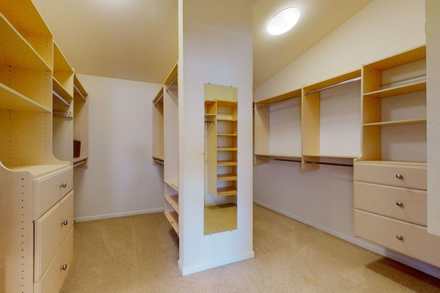 walk in closet with vaulted ceiling and light colored carpet