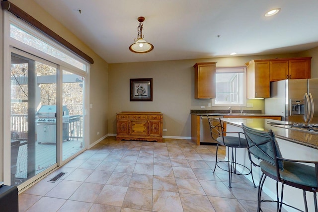 kitchen featuring hanging light fixtures, light tile patterned floors, a healthy amount of sunlight, and appliances with stainless steel finishes