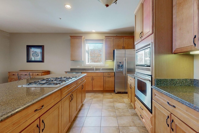 kitchen with light tile patterned flooring, appliances with stainless steel finishes, sink, and dark stone counters