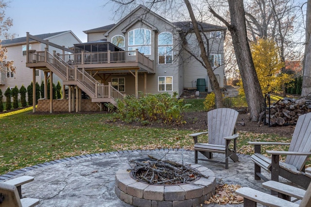 back of property featuring a wooden deck, a fire pit, a patio area, and a lawn