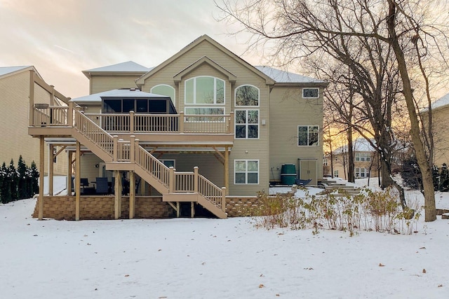 snow covered rear of property with a deck