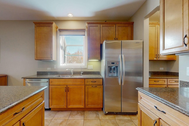 kitchen featuring dark stone countertops, sink, light tile patterned floors, and stainless steel appliances