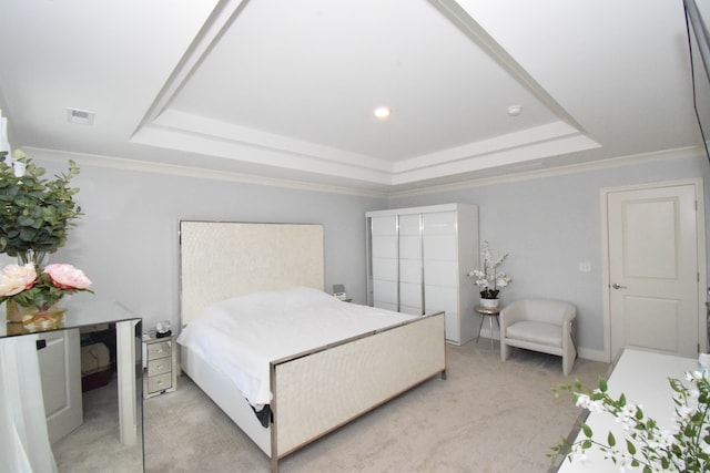 bedroom featuring crown molding, light carpet, and a tray ceiling