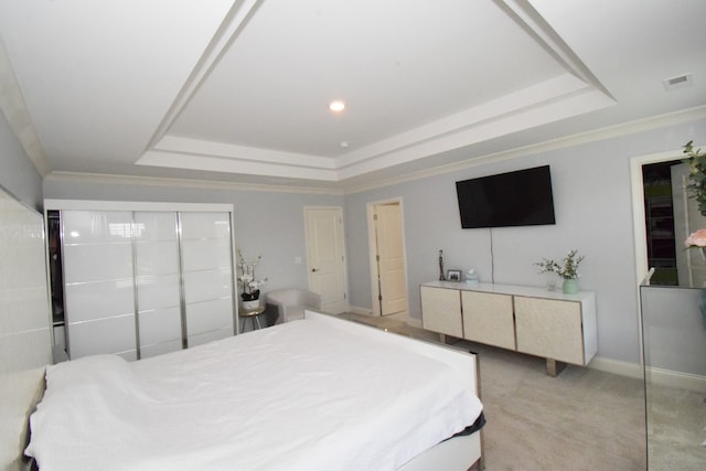 bedroom featuring crown molding, a tray ceiling, carpet flooring, and a closet