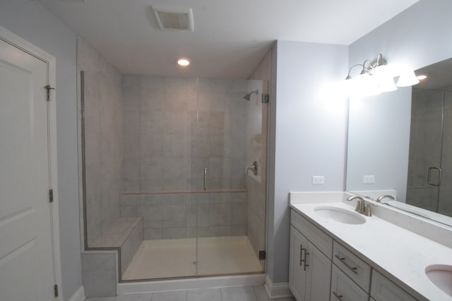 bathroom with a shower with shower door, double sink vanity, and tile patterned flooring