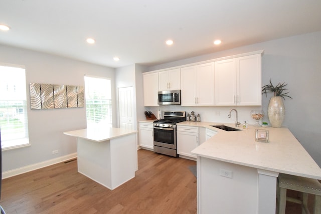 kitchen featuring appliances with stainless steel finishes, a wealth of natural light, sink, and light hardwood / wood-style floors