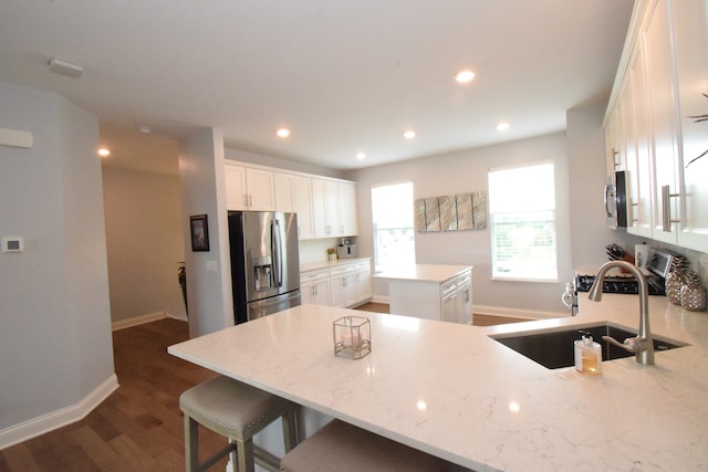 kitchen featuring dark wood-type flooring, stainless steel fridge with ice dispenser, light stone countertops, sink, and white cabinetry