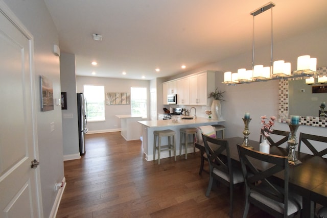 dining space with sink, dark wood-type flooring, and a chandelier