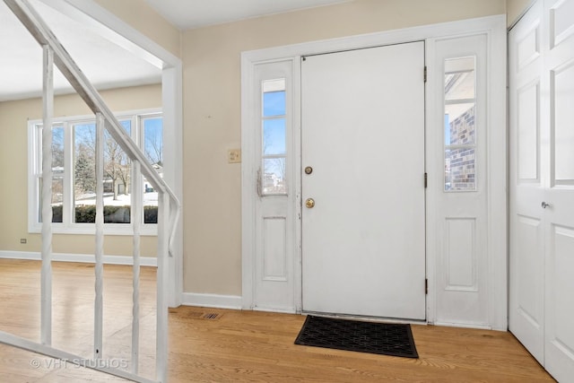 foyer entrance with visible vents, light wood-style flooring, and baseboards