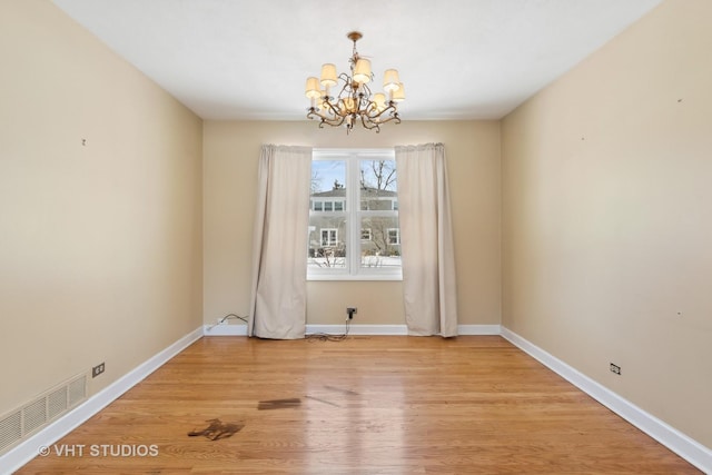 unfurnished dining area with light wood-style floors, baseboards, visible vents, and a notable chandelier