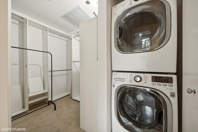 clothes washing area with light carpet and stacked washer and clothes dryer