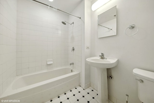 bathroom featuring toilet, tile patterned flooring, and tiled shower / bath