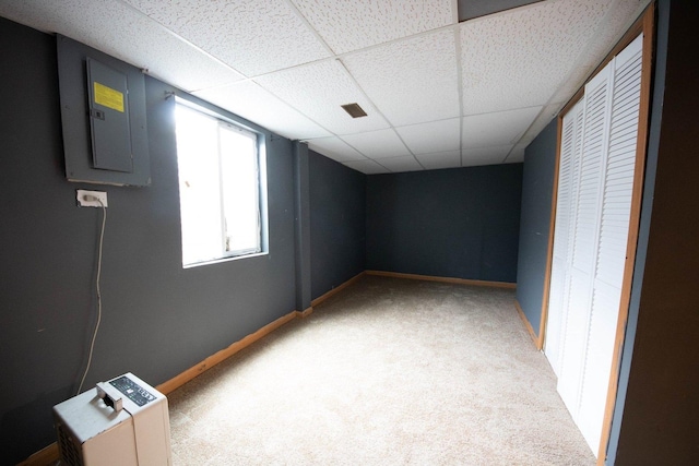 carpeted spare room with electric panel and a drop ceiling