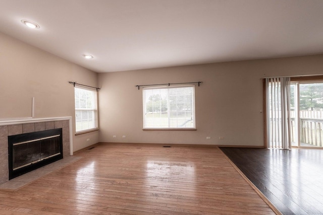 unfurnished living room featuring light wood-type flooring and a tiled fireplace