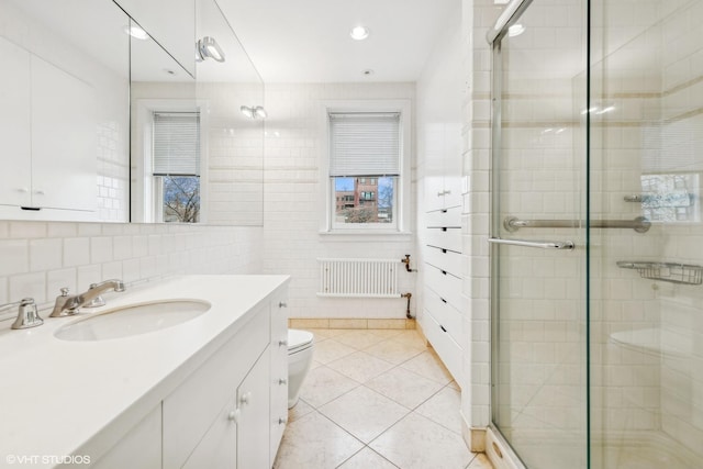 bathroom featuring tile patterned floors, a shower with door, and radiator